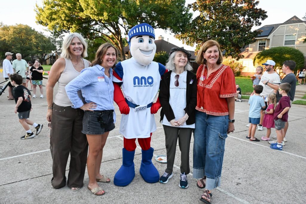 Four women posing for a photo with the National Night Out mascot