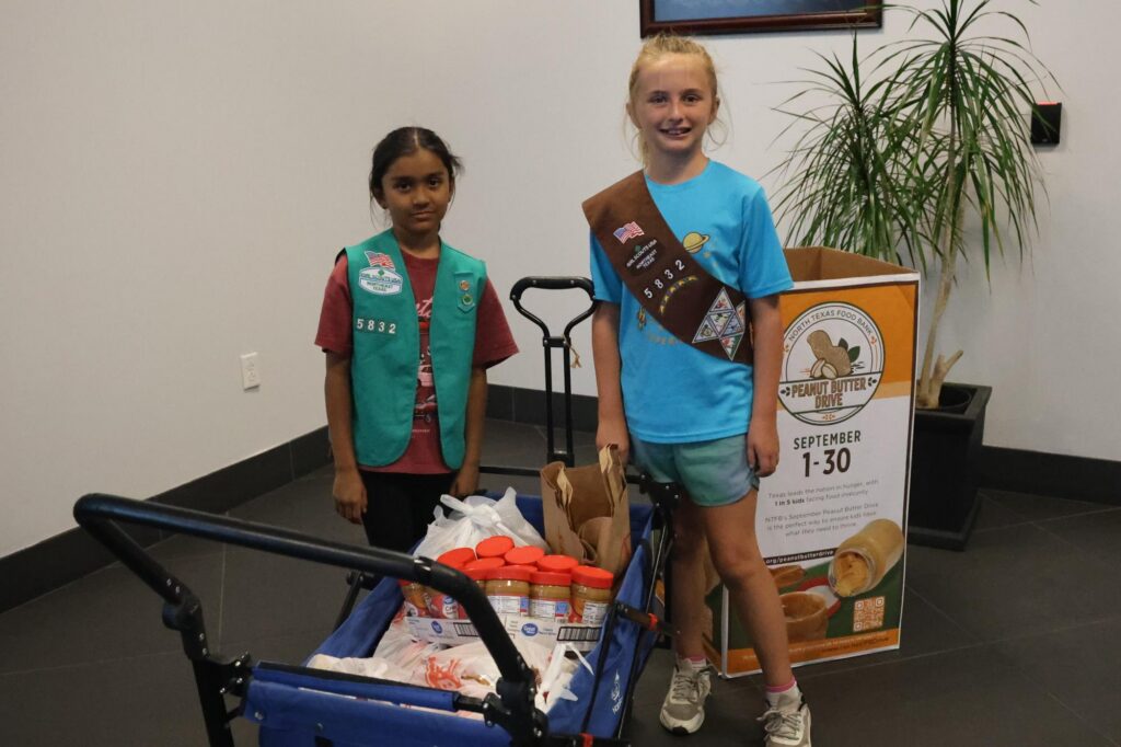 Picture showing two girl scout members donating peanut butter
